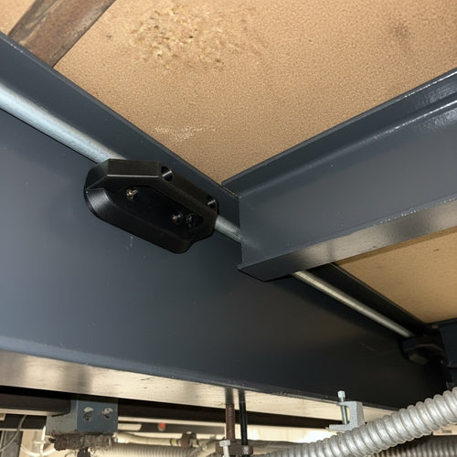Cold Composites black carbon fiber MagLug magnetic handle system attached to metal beams, holding a conduit pipe.