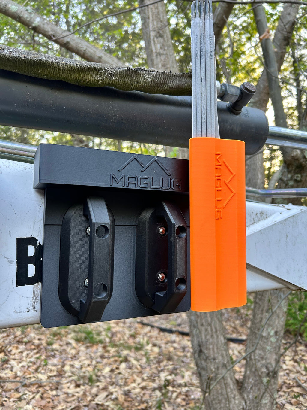 Cold Composites MagLug workstation with two magnetic handles and an orange holder for welding rods attached to a metal surface outdoors.